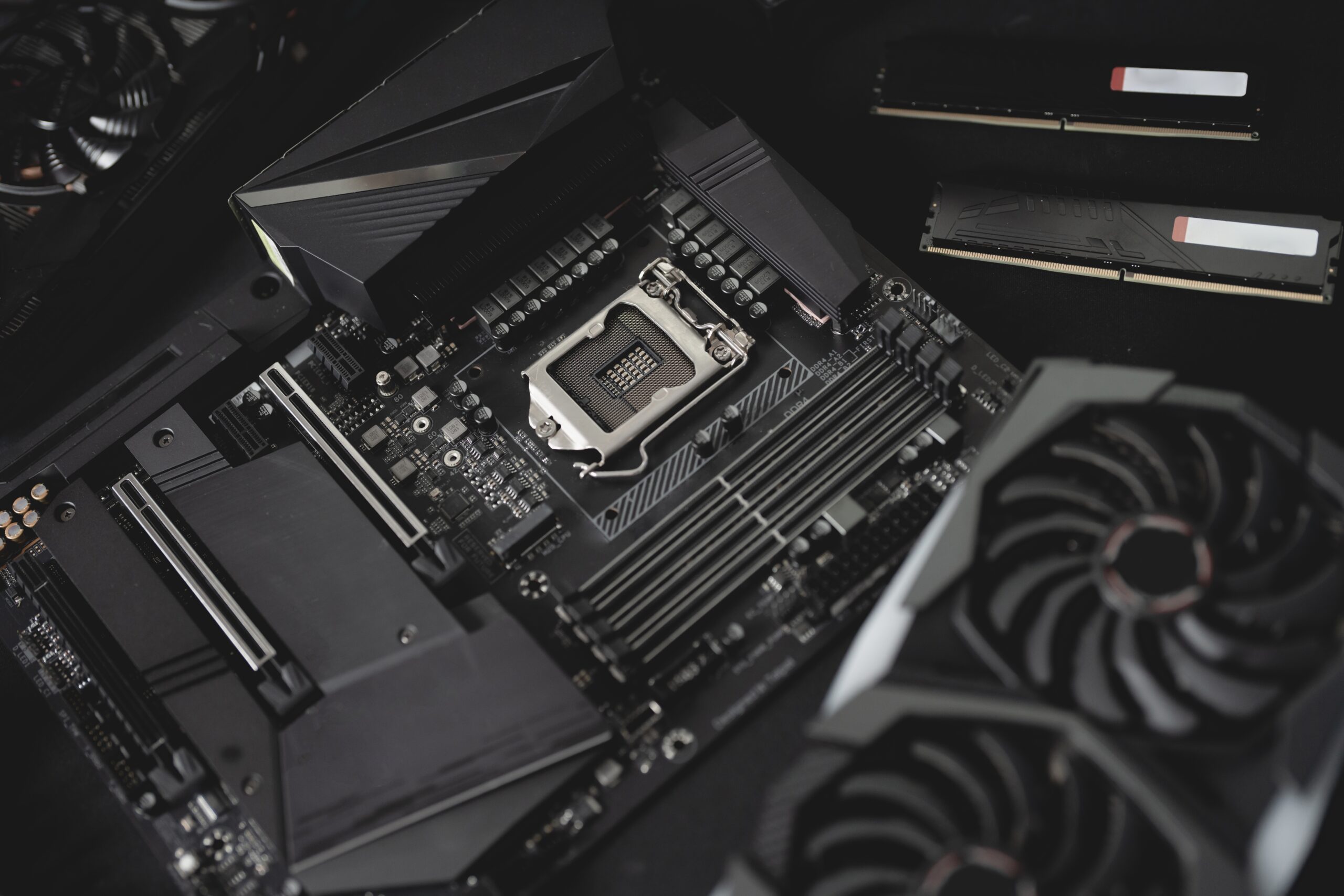 Close-up of a computer motherboard with a CPU socket, RAM slots, and cooling fans, showcasing essential components for building a high-performance PC.