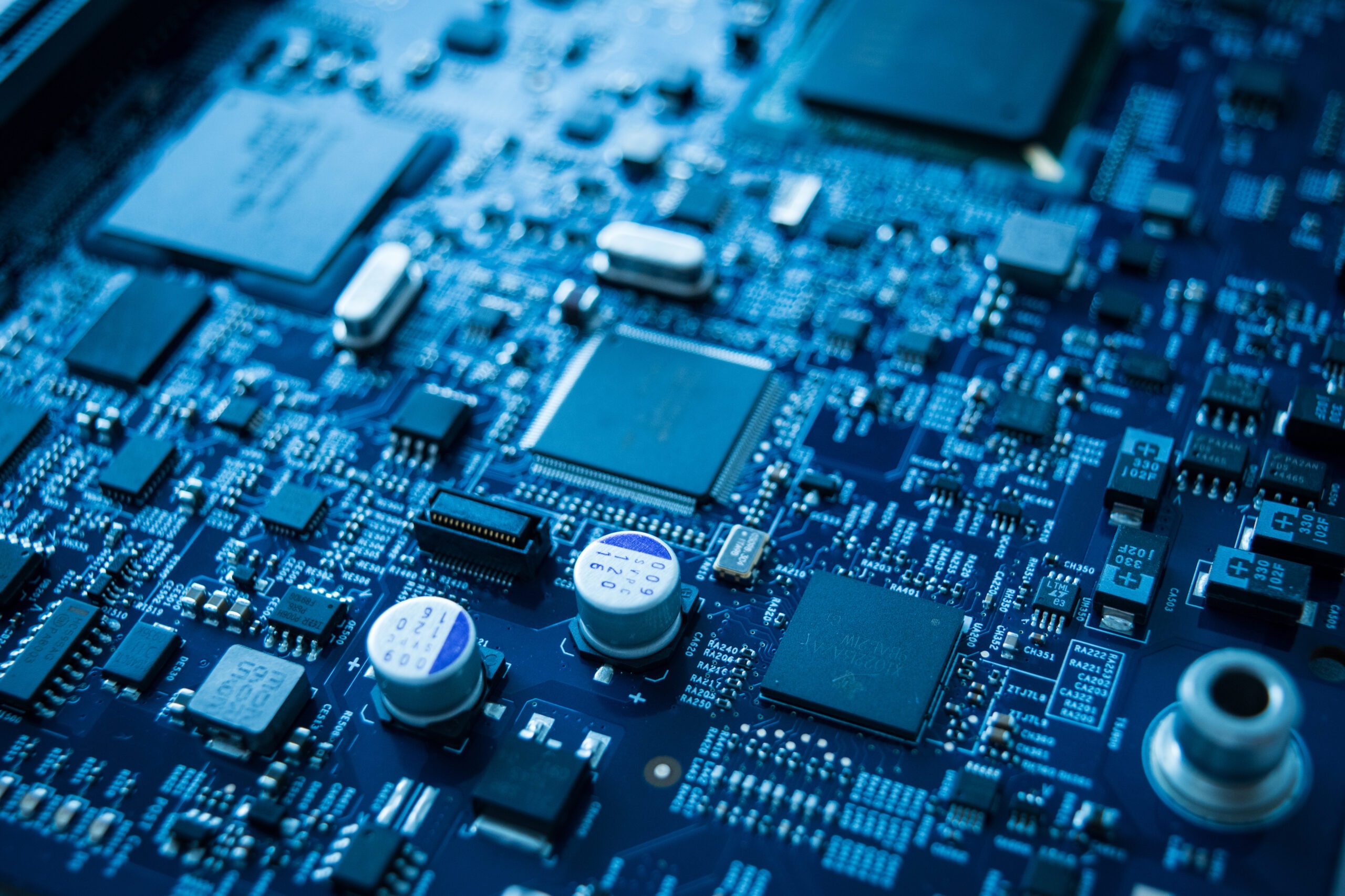 Close-up of a blue electronic circuit board featuring various integrated circuits and components, highlighting modern technology’s intricate design.